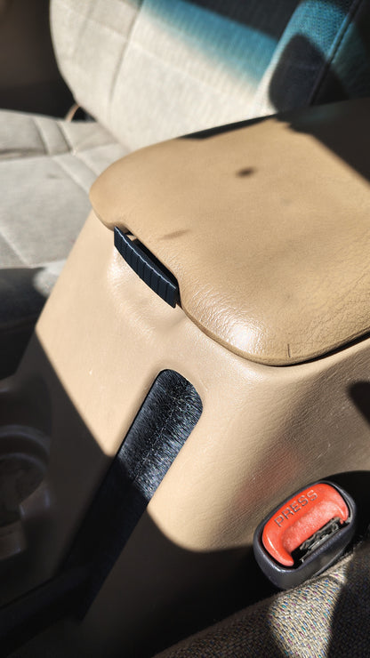 Black replacement latch installed on tan Jeep Cherokee XJ center console
